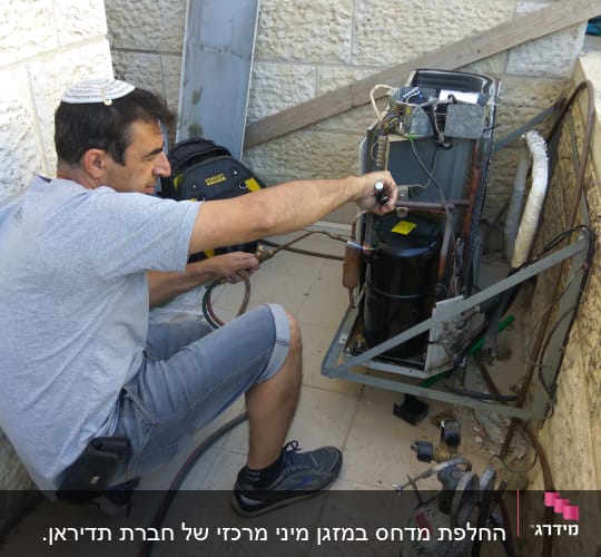 טכנאי מתקין מזגן עם כלים וצינורות